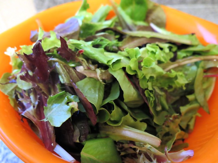 A bowl of mixed greens, including lettuce, arugula, and chicory